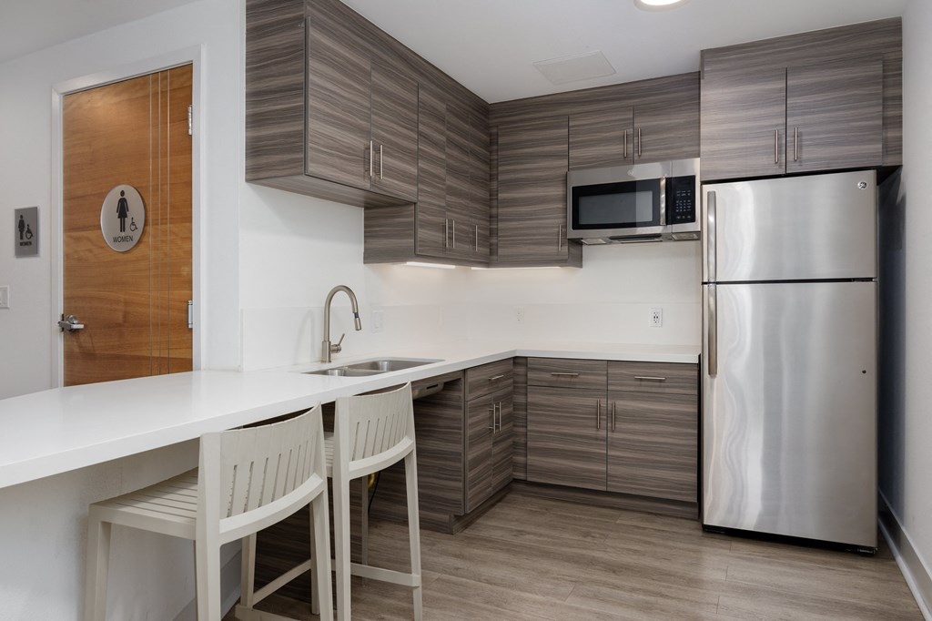 a kitchen with a white counter top and a stainless steel refrigerator