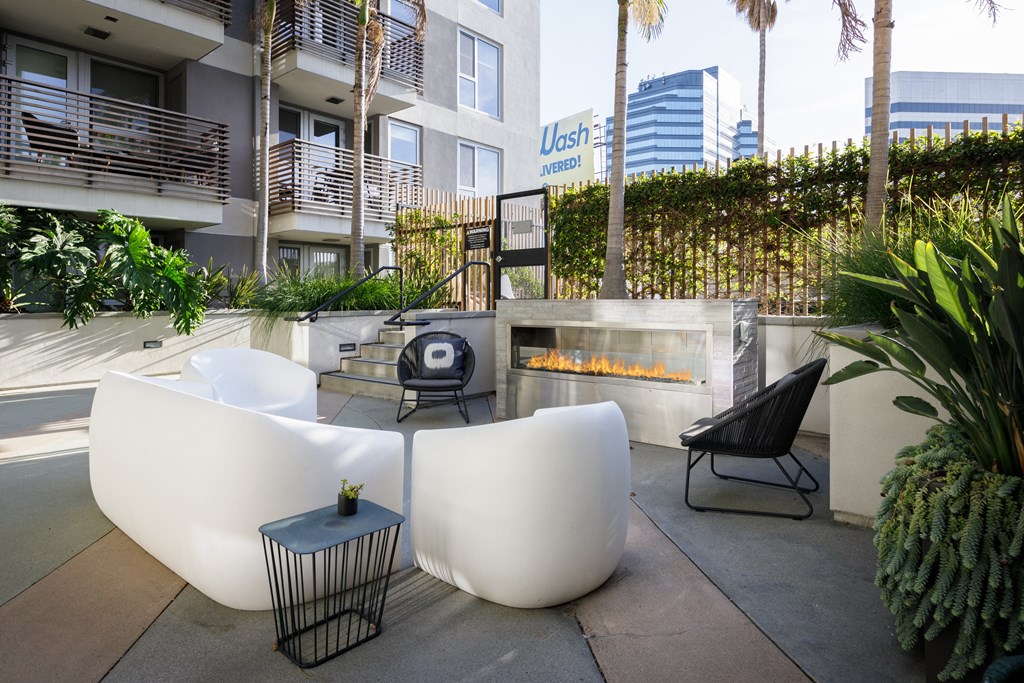 a seating area with a fire pit and chairs in front of a building