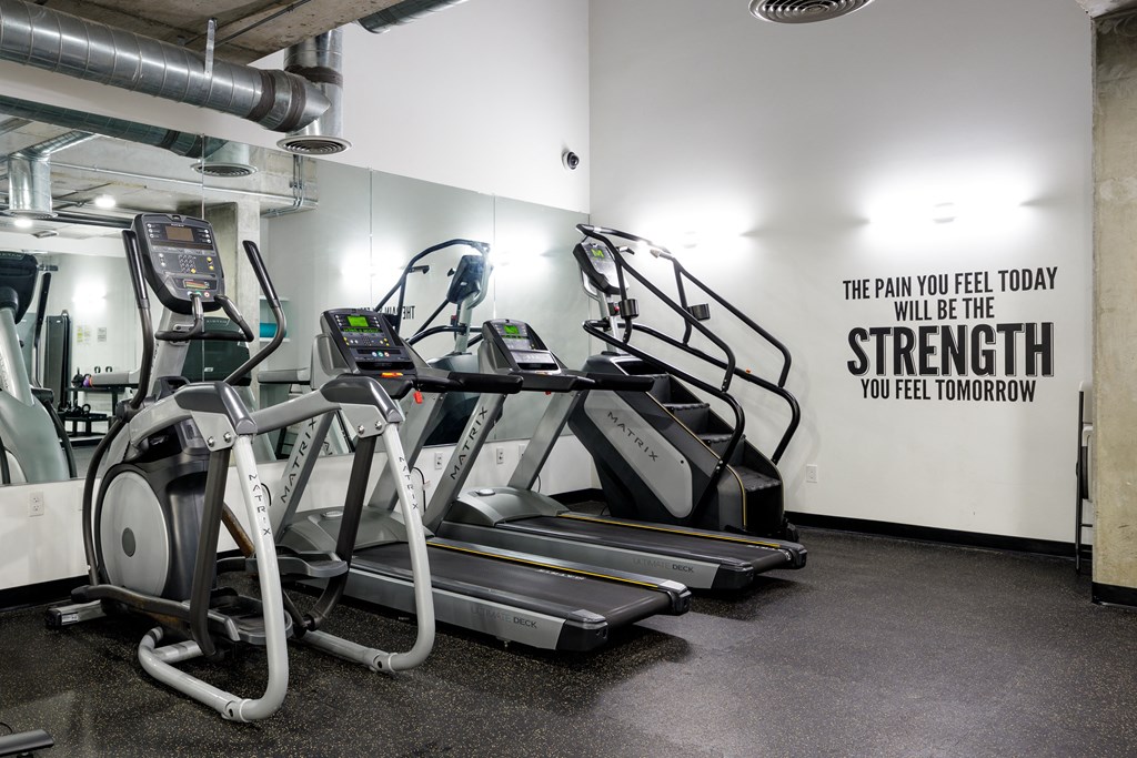 a row of treadmills in a gym with a wall quote from the gym