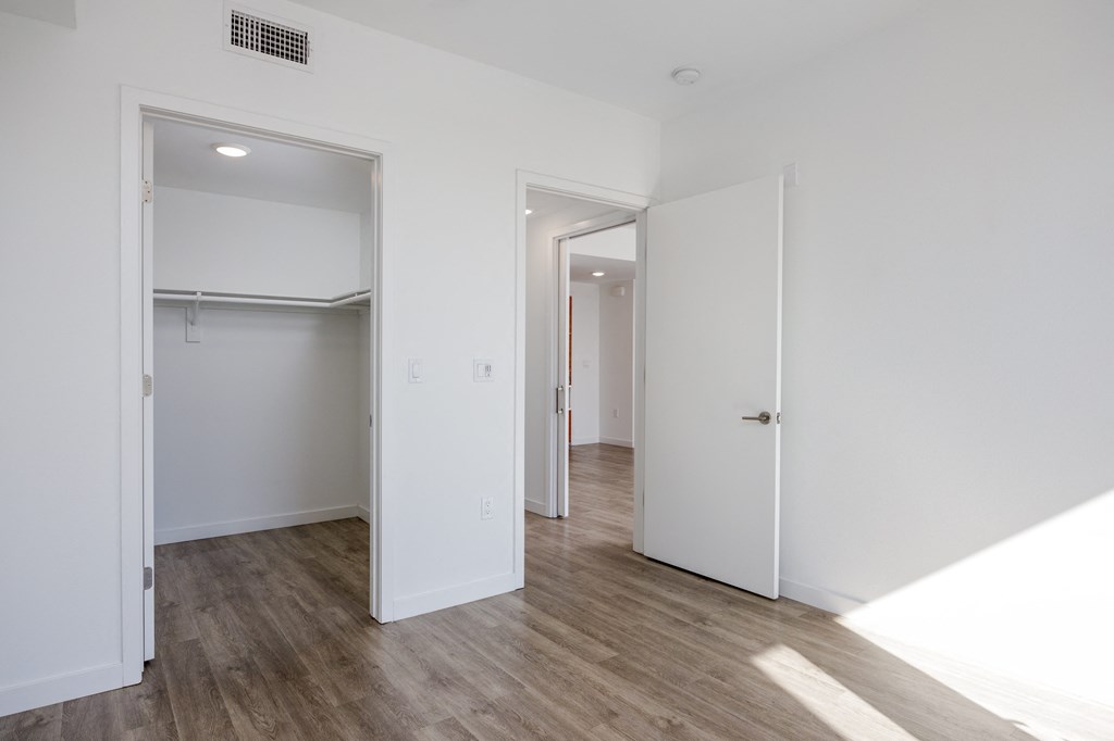 a bedroom with white walls and a door to a closet