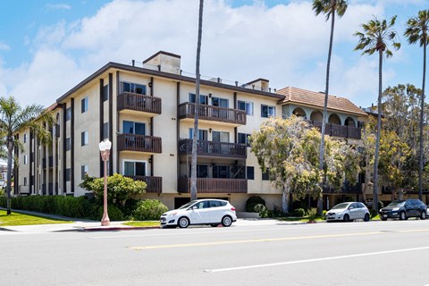 an apartment building on the corner of a street with cars