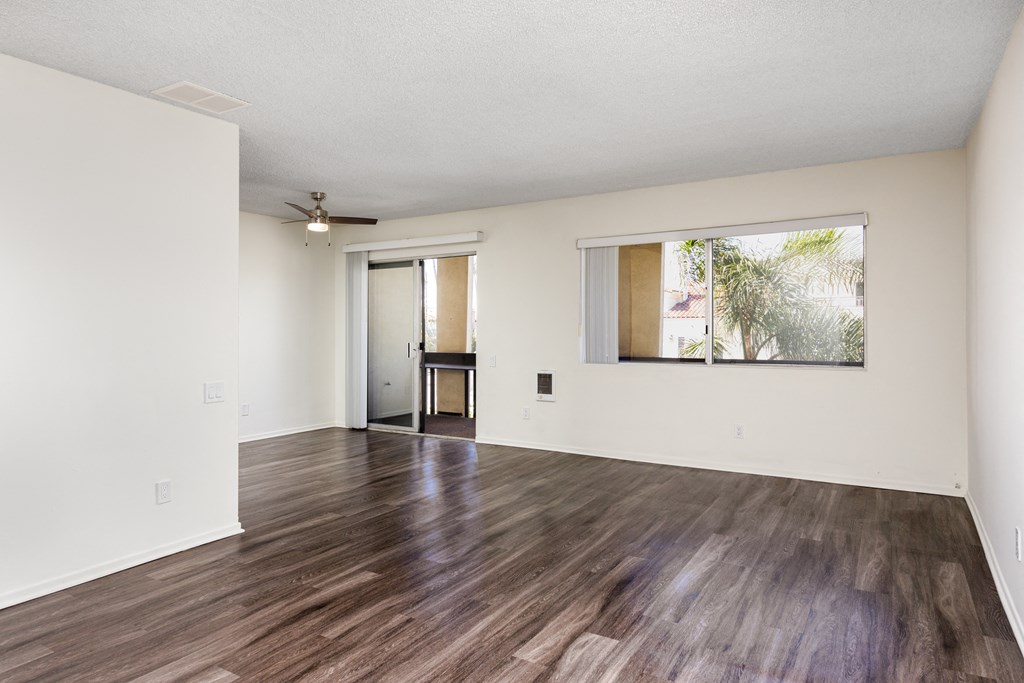 an empty living room with hard wood floors and a window