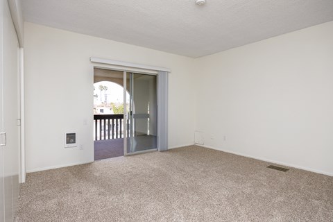 an empty living room with an open door to a balcony