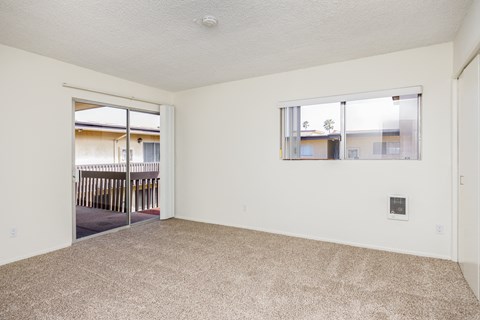 an empty living room with a window and a door to a balcony