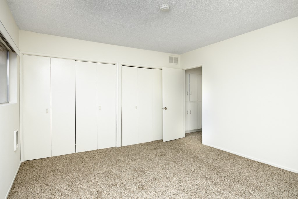 an empty room with white closets and carpeting