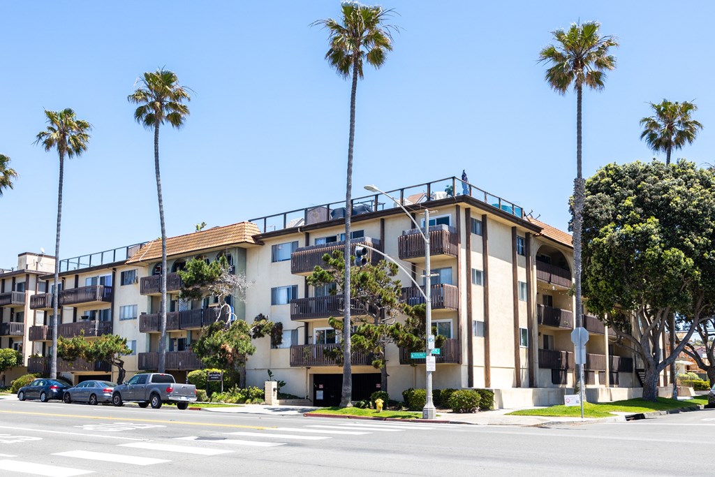 an apartment building on a street with palm trees