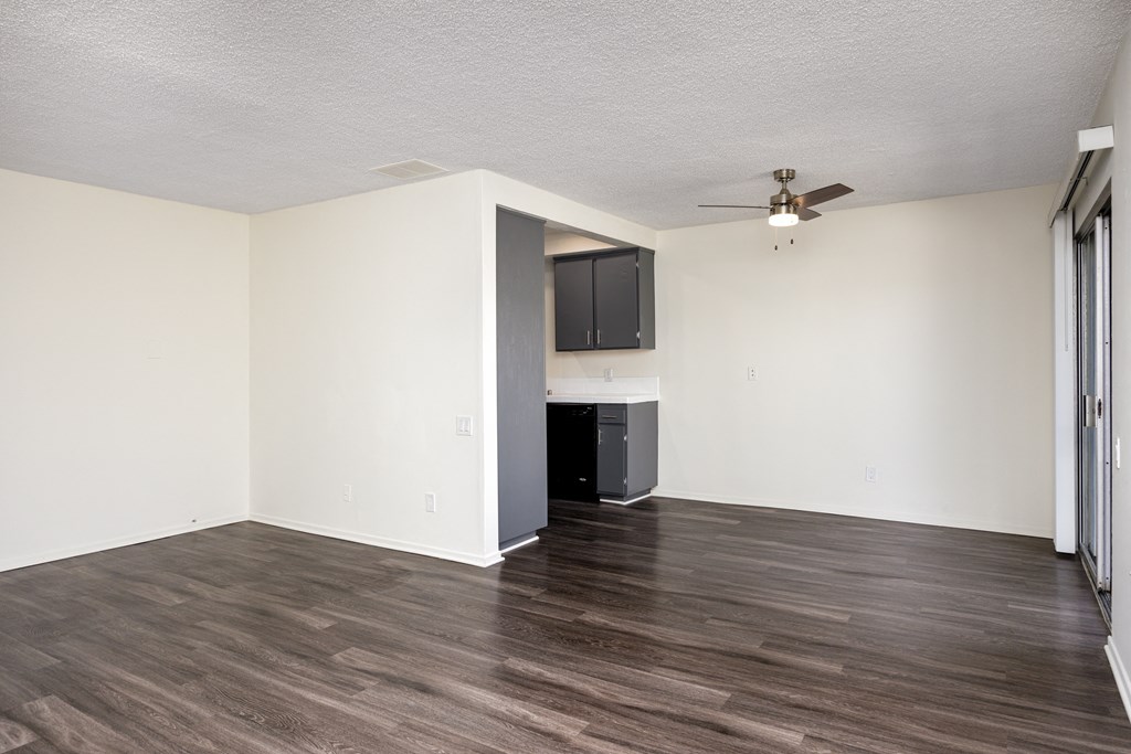 an empty living room with white walls and a ceiling fan