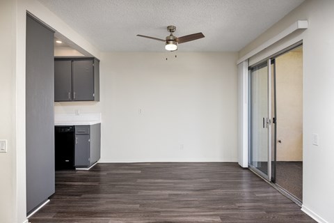 an empty living room with a ceiling fan and a kitchen