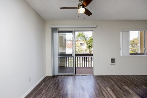 an empty living room with a sliding glass door to a balcony