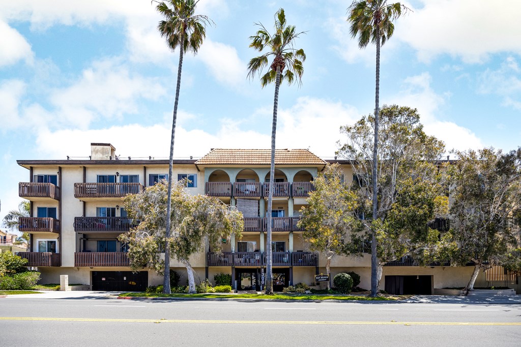 an apartment building with palm trees in front of it