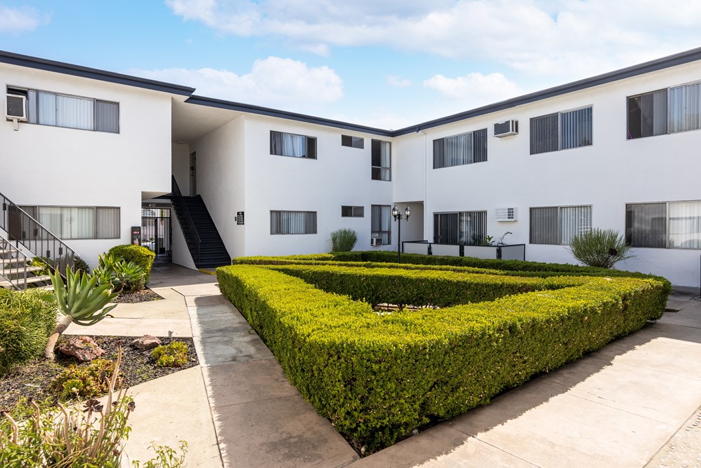 an exterior view of a building with hedges and a courtyard