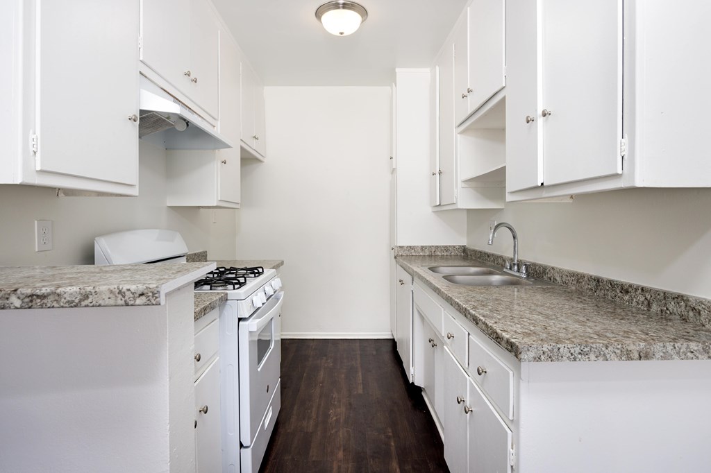 a kitchen with white appliances and granite counter tops and white cabinets