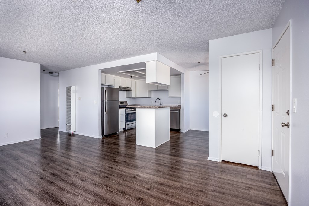 A kitchen with white cabinets and a wooden floor.