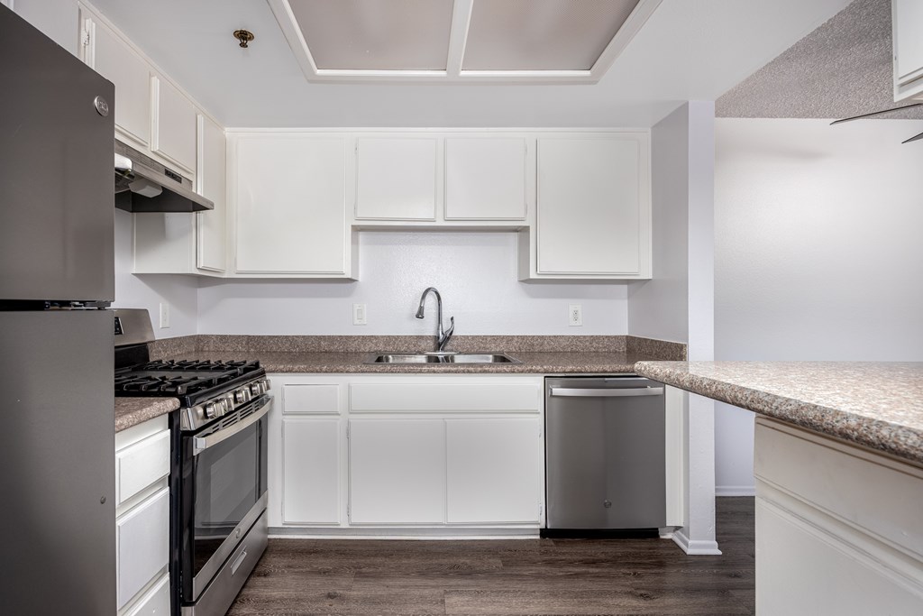 A kitchen with white cabinets and a granite countertop.