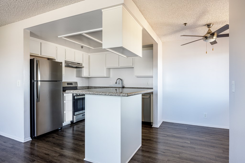 A kitchen with a refrigerator, sink, and stove.