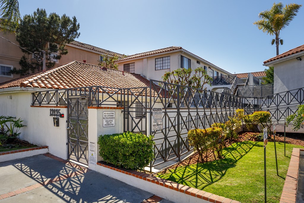 A white house with a black gate and a brown roof.