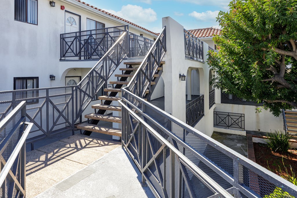 A staircase with a metal railing leads up to a white building.