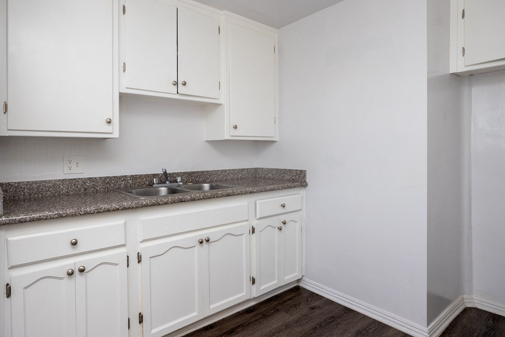 a kitchen with white cabinets and granite counter top and a sink