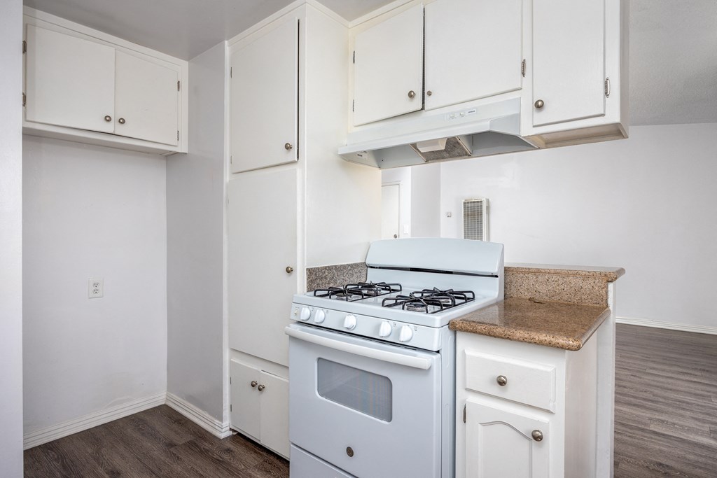 an empty kitchen with white appliances and white cabinets