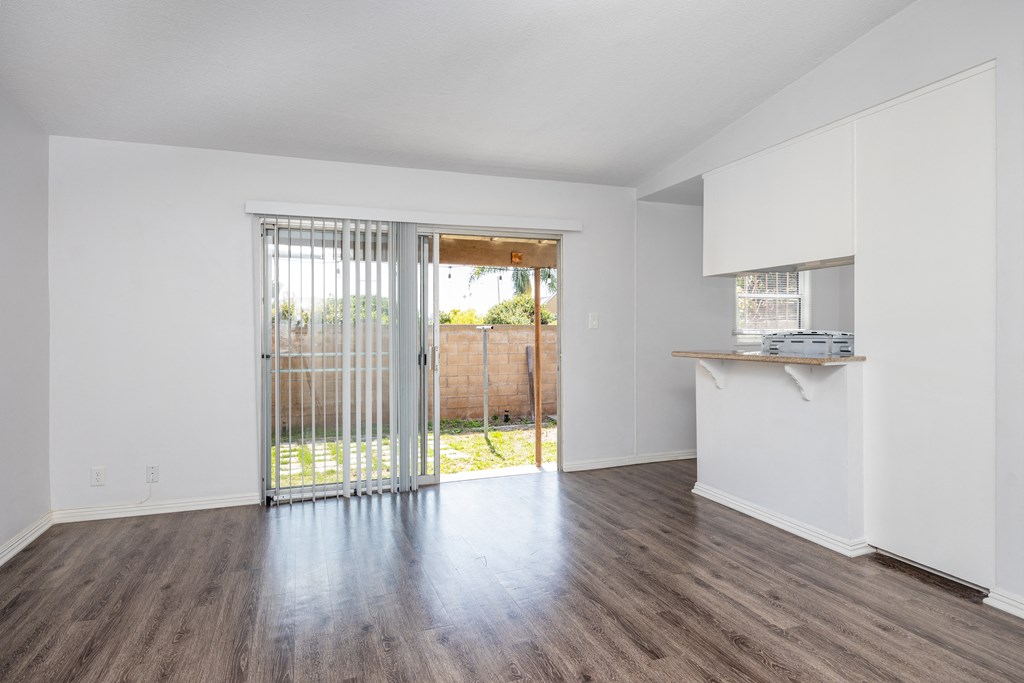 an empty living room with a sliding glass door to a backyard