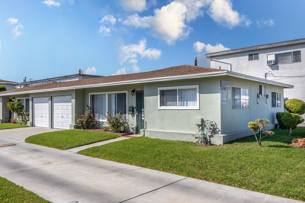 a blue and white house with a driveway and lawn