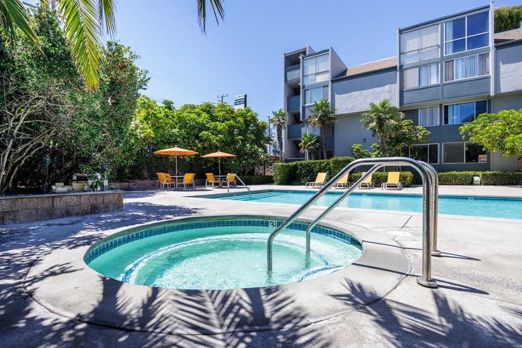 a hot tub in a pool with an apartment building in the background