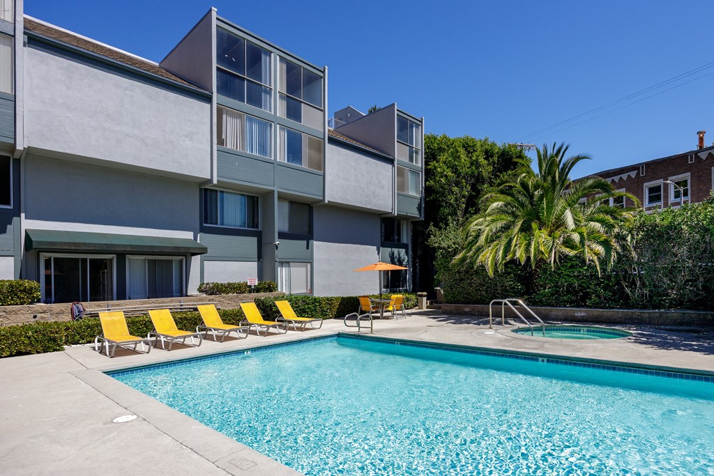 a swimming pool with yellow chairs in front of a building