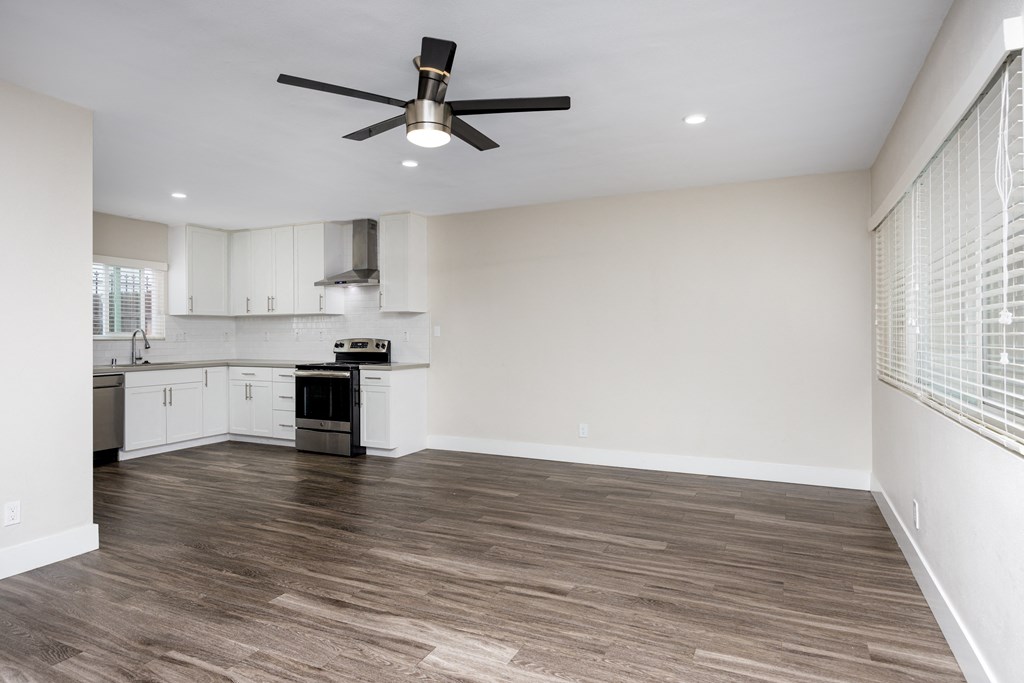 an empty kitchen and living room with a ceiling fan