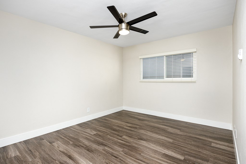 an empty room with a ceiling fan and a window