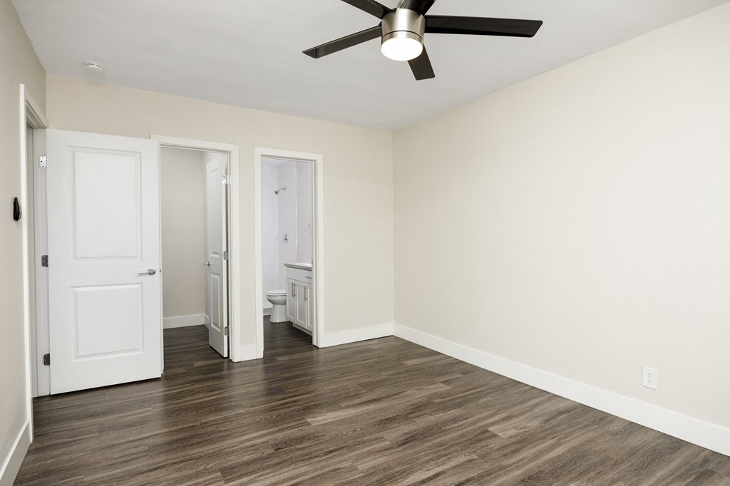 an empty living room with white walls and a ceiling fan