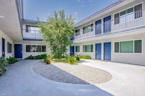 the entrance to a building with blue doors and a tree in the center
