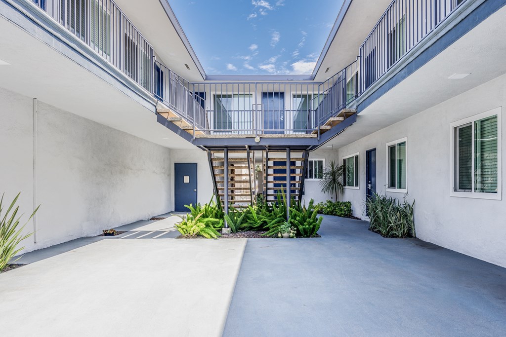 the courtyard of a white building with a blue door