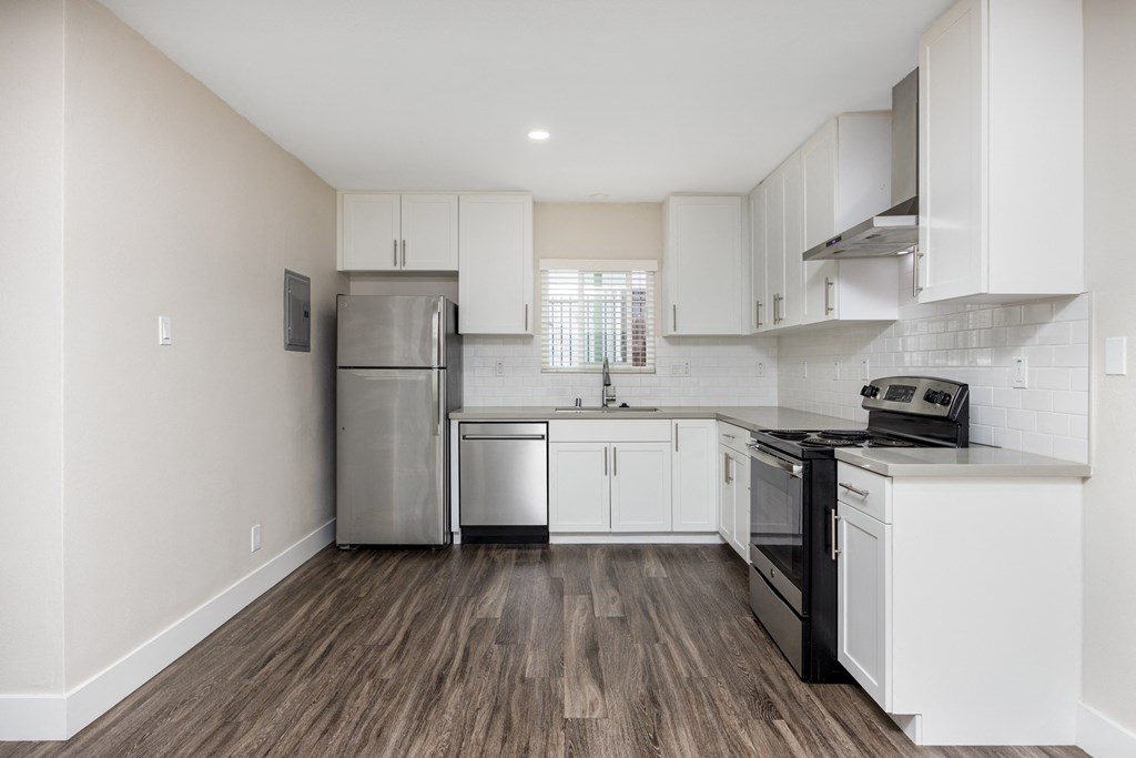 an empty kitchen with white cabinets and stainless steel appliances