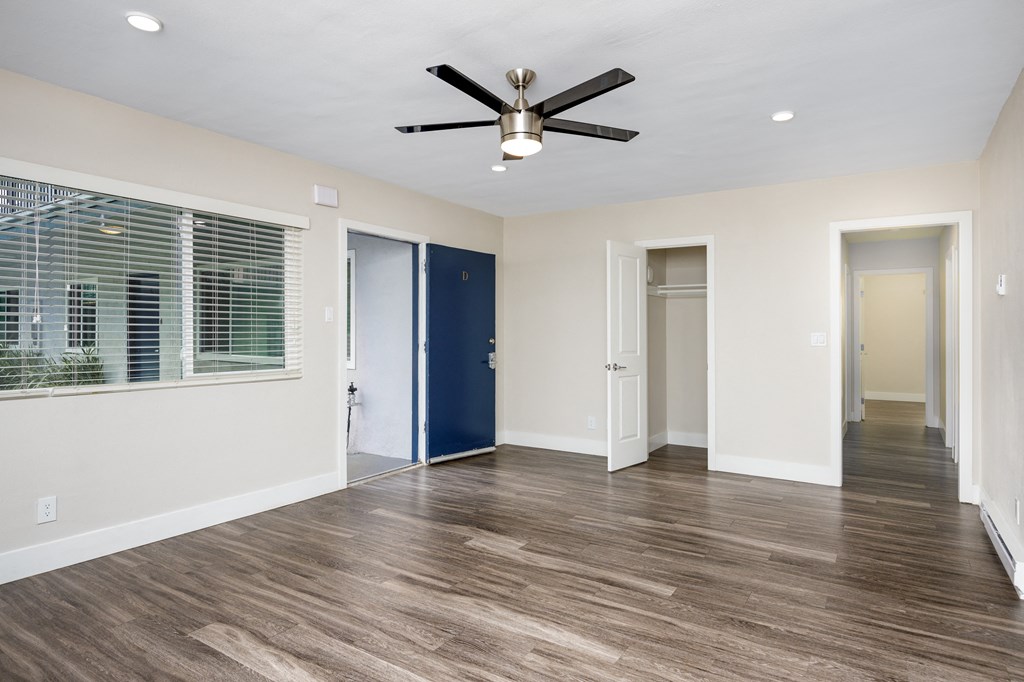 an empty living room with a ceiling fan and a window