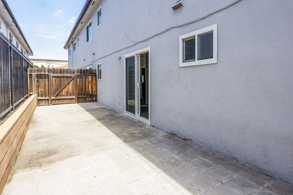 the outside of a white house with a patio and a wooden fence