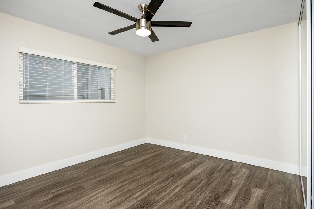 an empty room with a window and a ceiling fan
