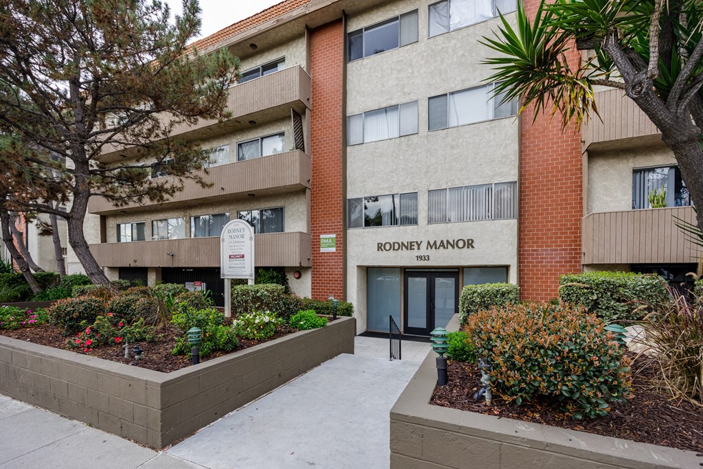 an apartment building with a sidewalk and garden in front of it