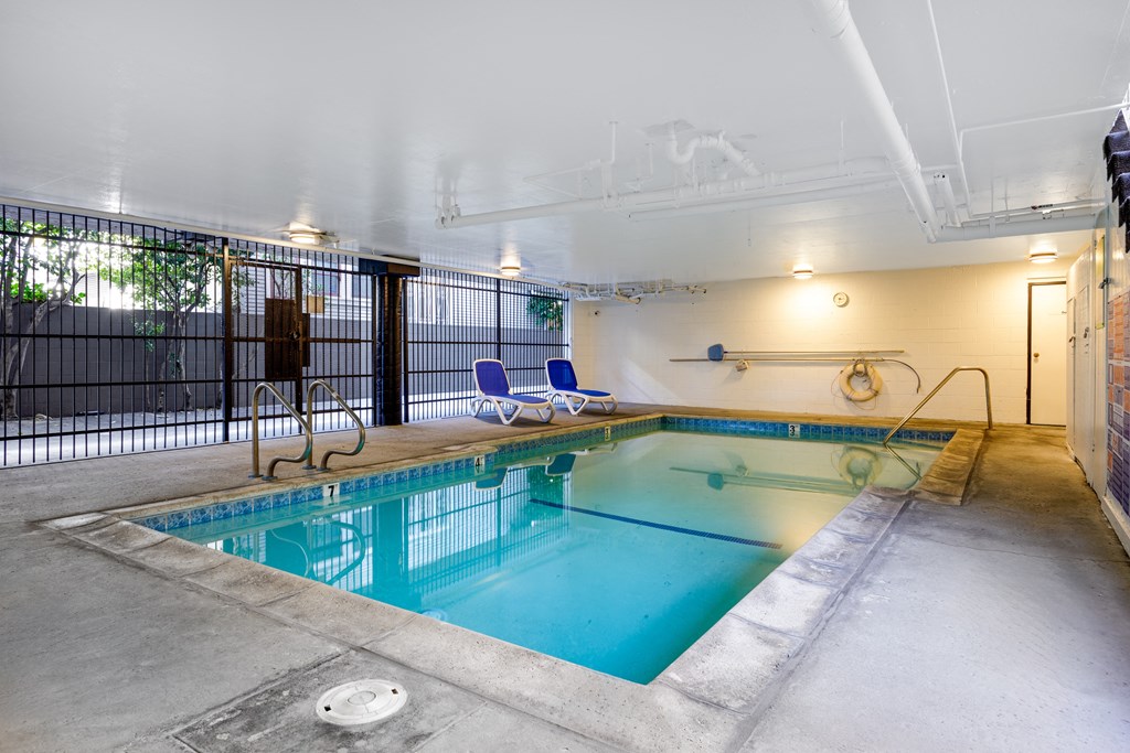 a swimming pool with chairs and a fence around it