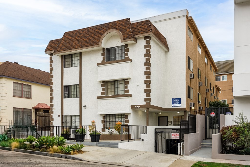 A white and brown building with a black gate in front.