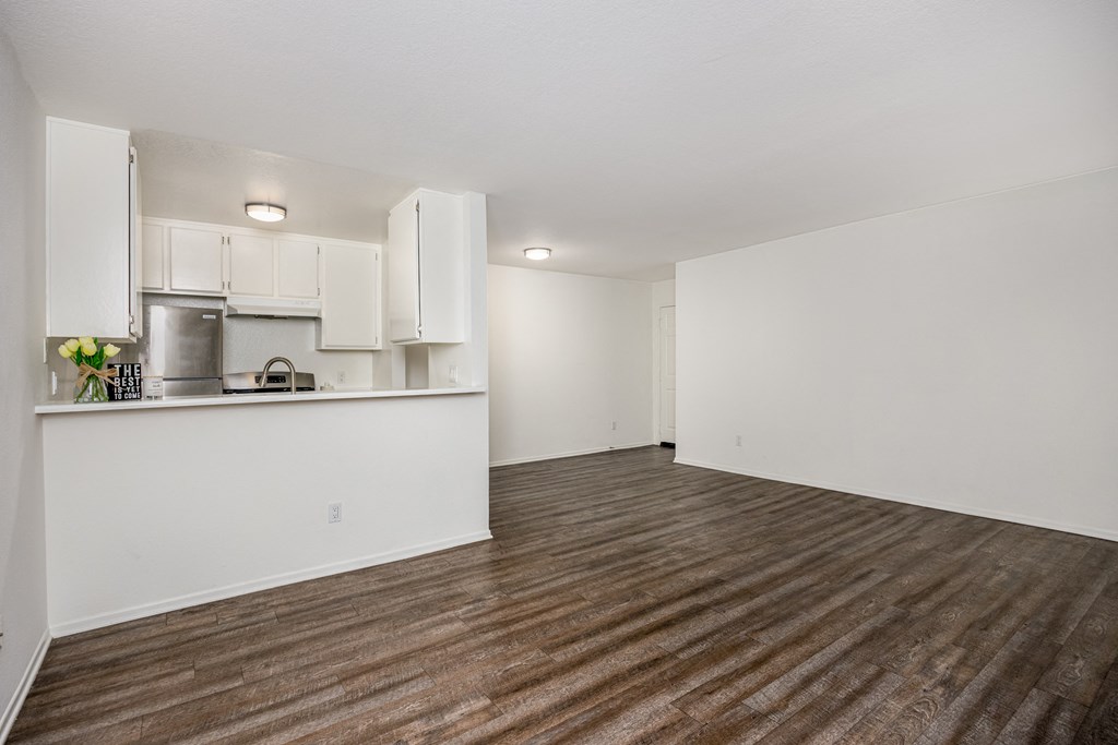 A kitchen with white cabinets and a wooden floor.