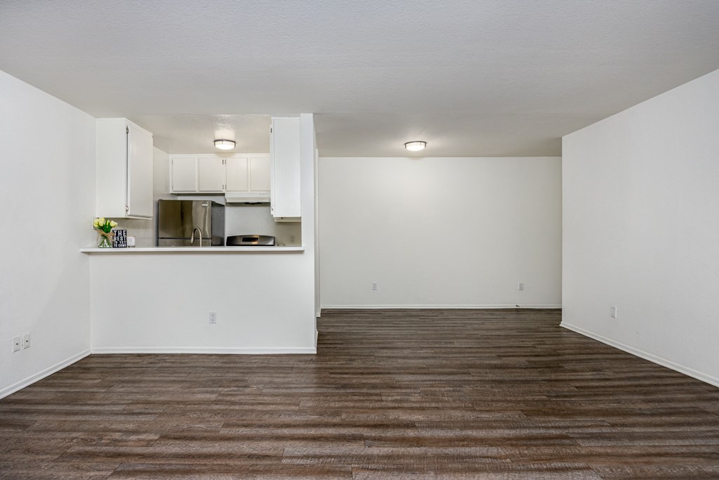 A kitchen with white cabinets and a wooden floor.