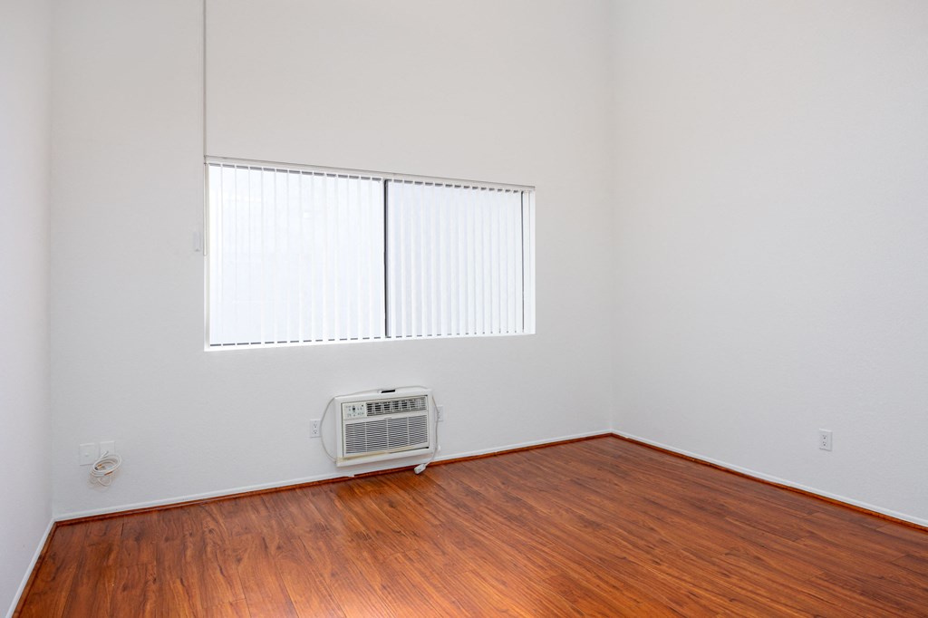 an empty room with a wood floor and an air conditioner