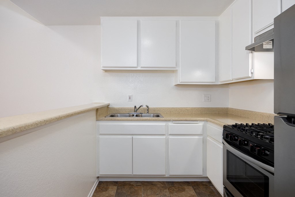 a kitchen with white cabinets and a sink and a stove