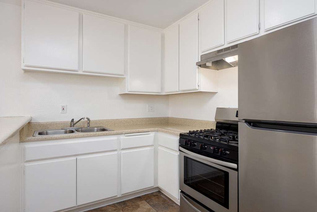 an empty kitchen with white cabinets and stainless steel appliances