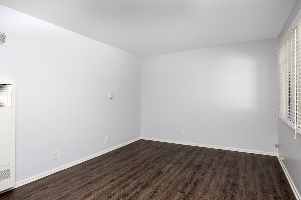 an empty room with wood floors and white walls