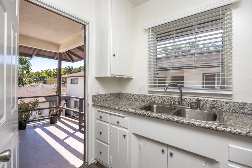 a kitchen with a sink and a window and a door to a balcony