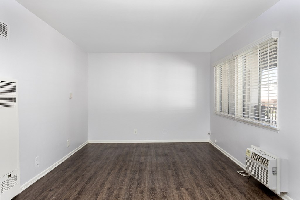 an empty room with white walls and wood floors and a window