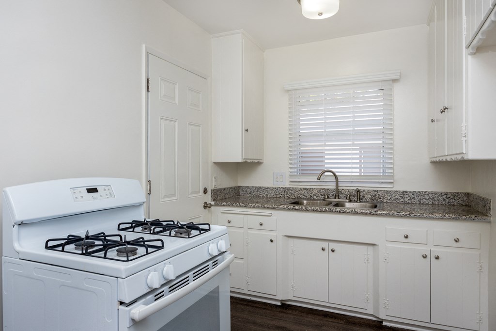 a kitchen with white appliances and granite counter tops and white cabinets