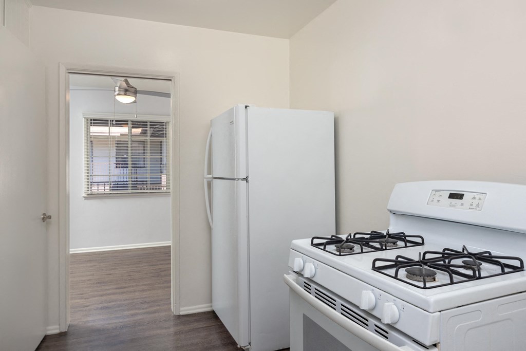 an empty kitchen with white appliances and a white refrigerator
