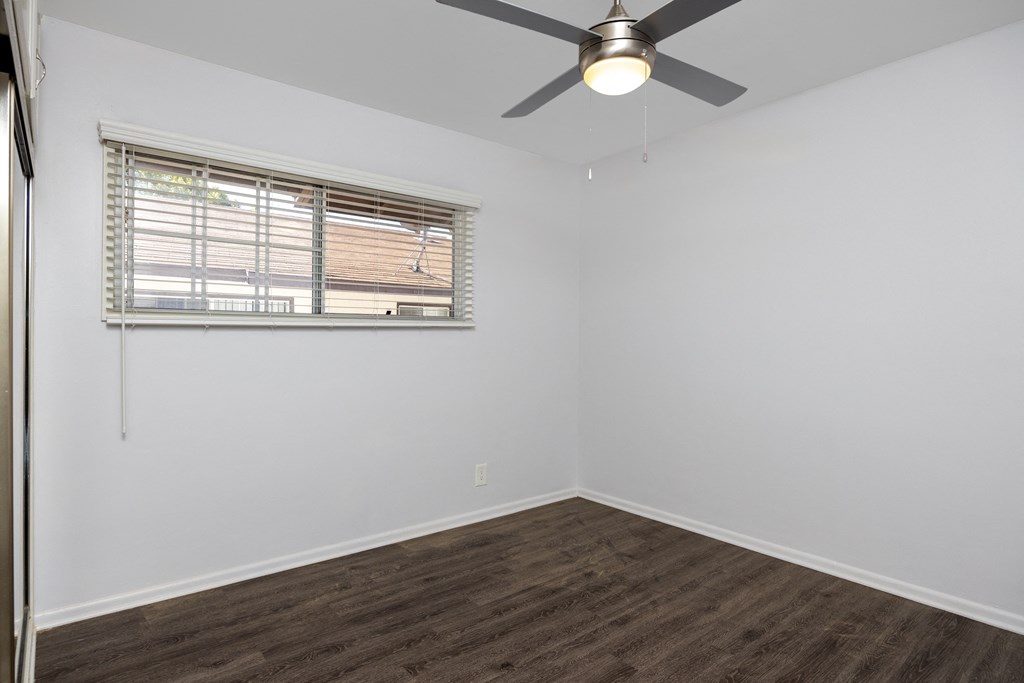 an empty room with a ceiling fan and a window